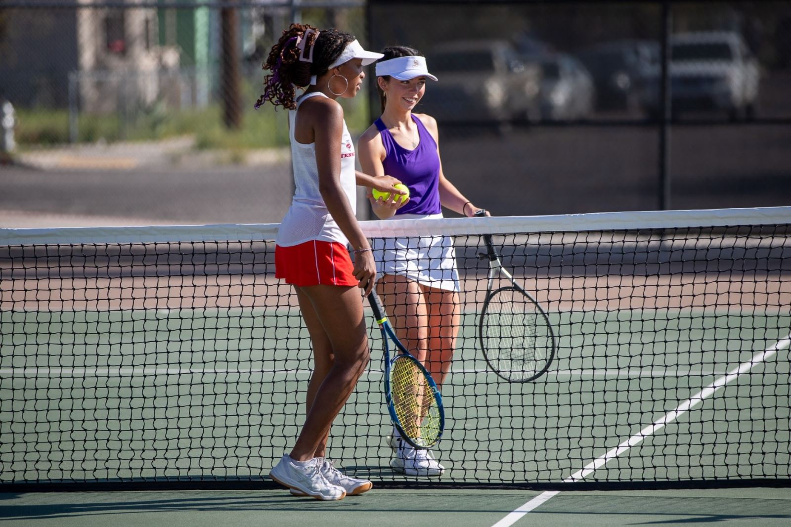A THMS girls tennis player and a Sabino girls tennis player hand off tennis balls over the net.