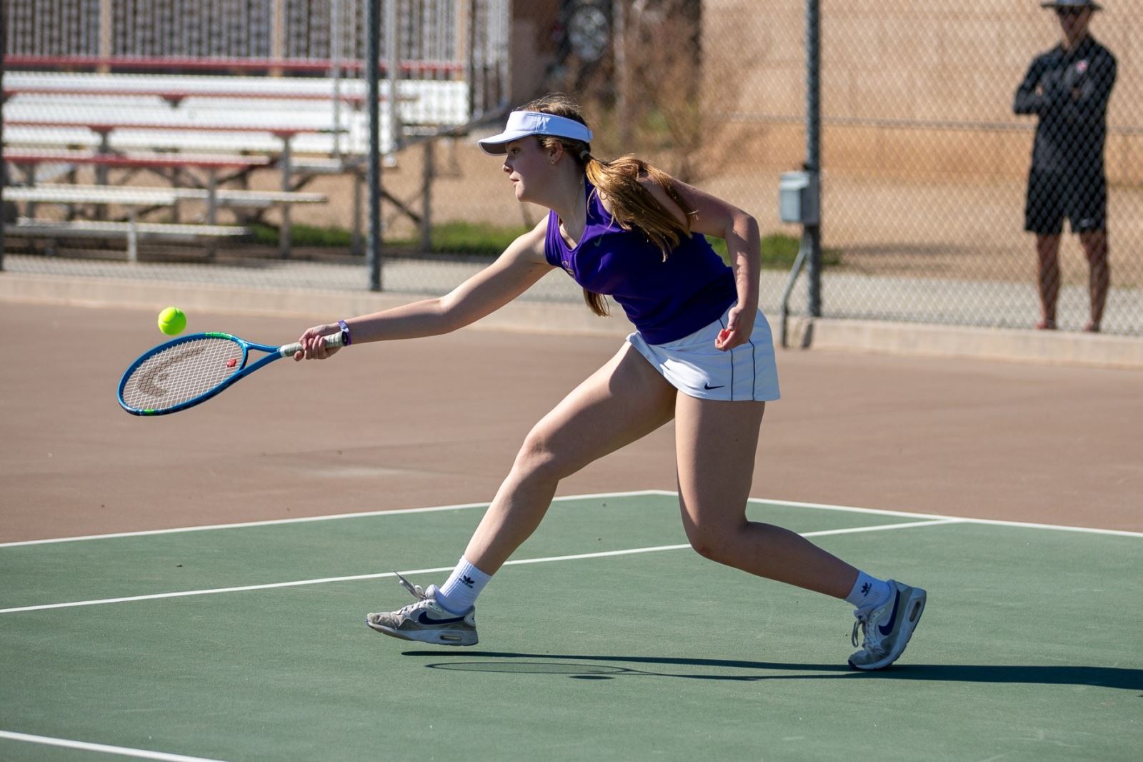A Sabino girls tennis player aims her racquet low to hit the ball.