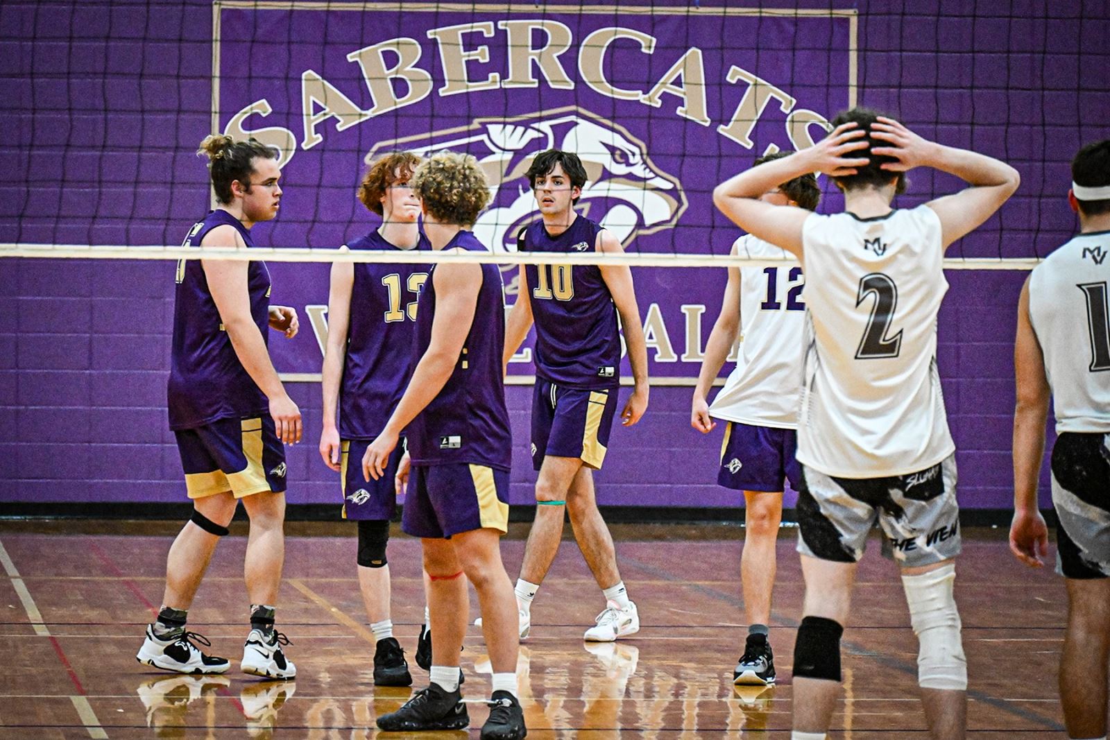 Sabino boys volleyball players gather by the net