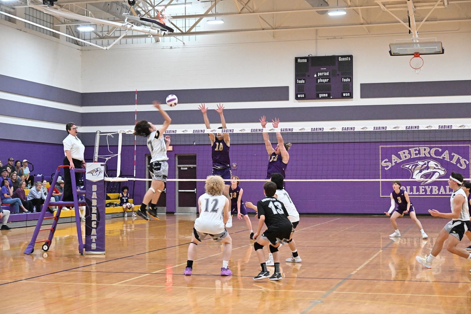The opposing team spikes the ball over the net to Sabino