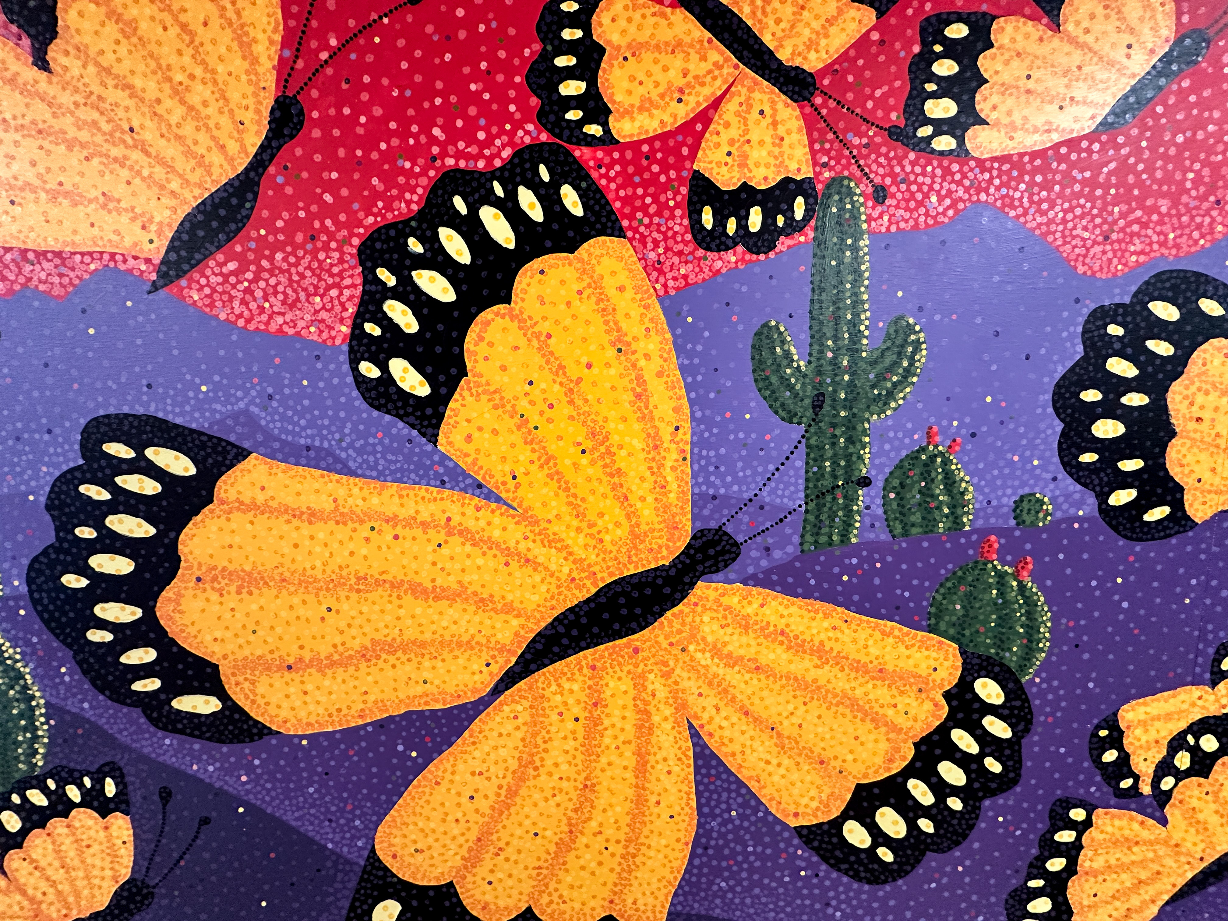 A colorful mural with orange butterflies and saguaro cactus