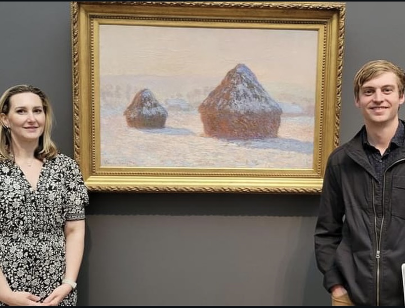 A student and teacher pose next to the student's painting