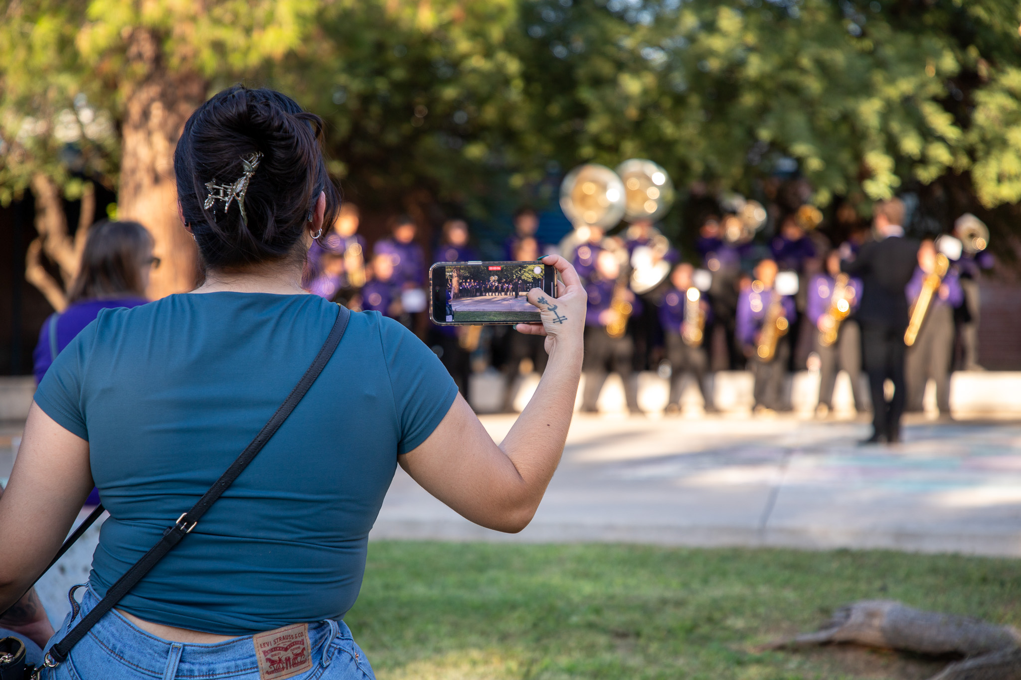 A parent captures a video of the marching band performance