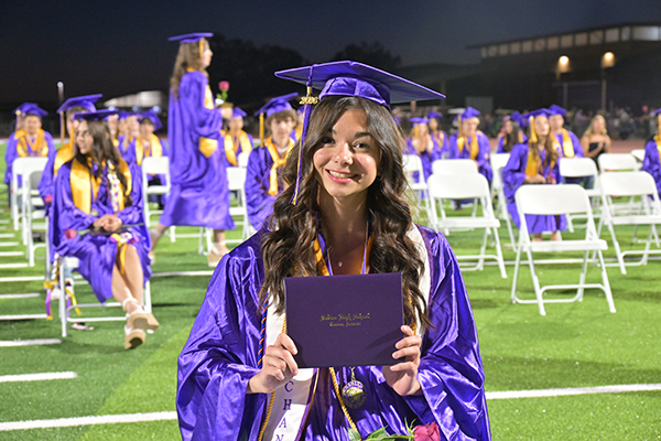 A graduate proudly holds up her diploma