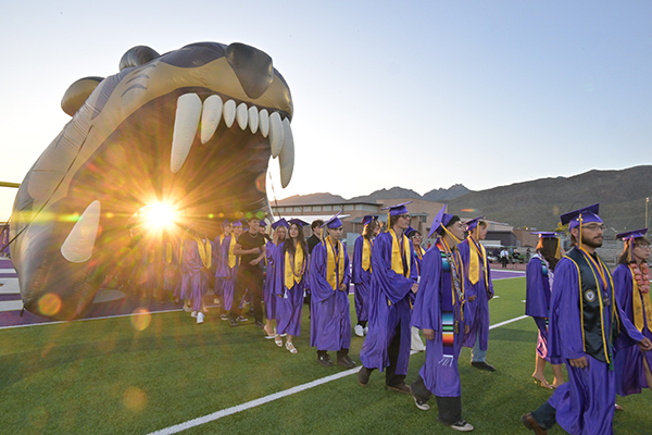 Students walk through the inflatable Sabercat head onto the football field for the graduation ceremony