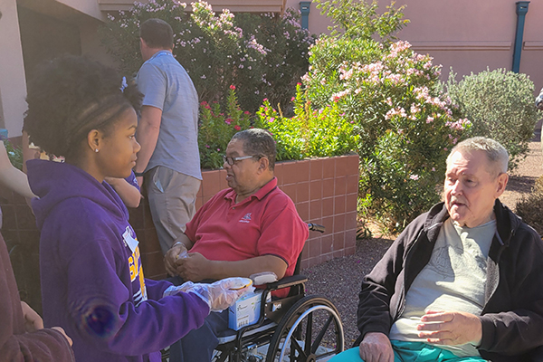 A teen girl hands out cookies to veterans at the VA Hospital