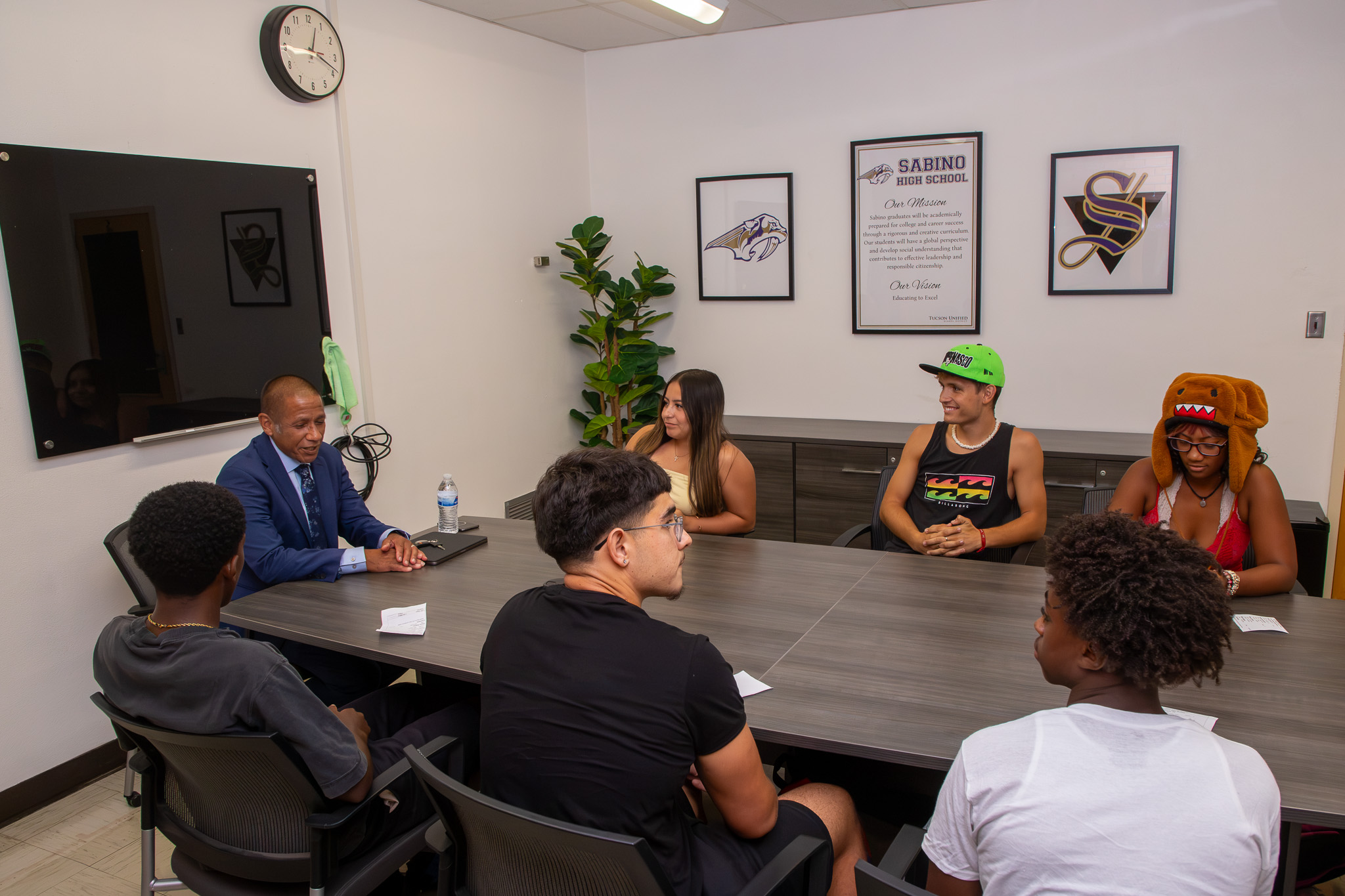 Dr.Trujillo and a group of students chat while sitting around a conference table