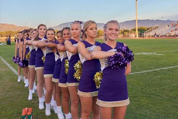 Cheerleaders lined up on football field 